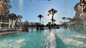 Relax by the serene pool surrounded by lush palm trees and a natural rock formation.