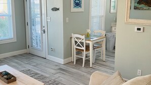 A living room with a beige sofa, a wooden coffee table, and a dining area with a white table and chairs. - HangLoose14AD-Beautiful Beach Cottage@ the Purple Parrot Resort/Perdido Key FL (Pensacola)