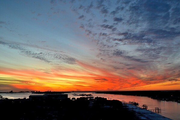 A sunset over a body of water with a dock and buildings in the foreground.