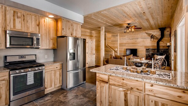 A modern kitchen with wooden cabinetry, stainless steel appliances, and a granite countertop.