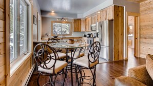 A modern kitchen with wooden cabinets, a stainless steel refrigerator, and a dining area with a round table and chairs.