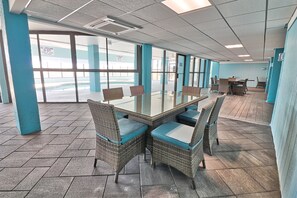 A conference room with a glass table and wicker chairs, large windows, and a view of a pool.
