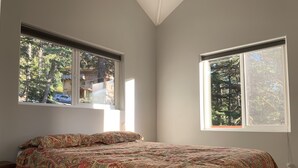 A bedroom with a bed, two windows, and a view of trees and a building outside. - Stunning, New 2 bedroom Unit Minutes from Alyeska Resort (Anchorage)