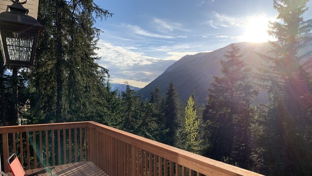 A wooden deck with a view of a mountain range and trees. - Stunning, New 2 bedroom Unit Minutes from Alyeska Resort (Anchorage)