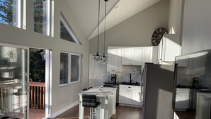 A modern kitchen with white cabinets, a central island, and a large window. - Stunning, New 2 bedroom Unit Minutes from Alyeska Resort (Anchorage)