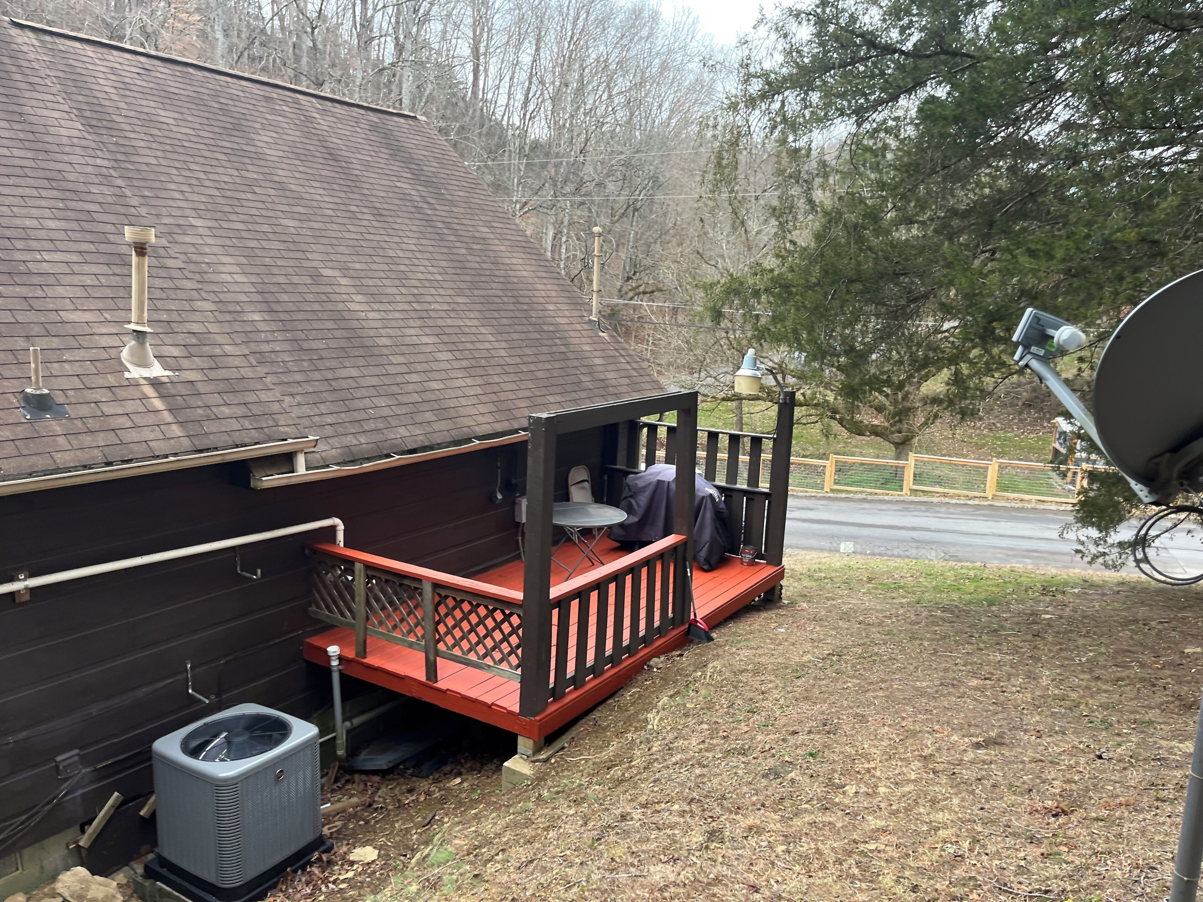 A building with a covered outdoor seating area, a satellite dish, and a paved driveway.