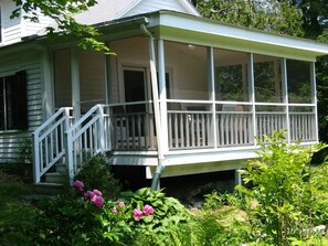 A house with a covered porch, a front door, and a staircase leading to the entrance.