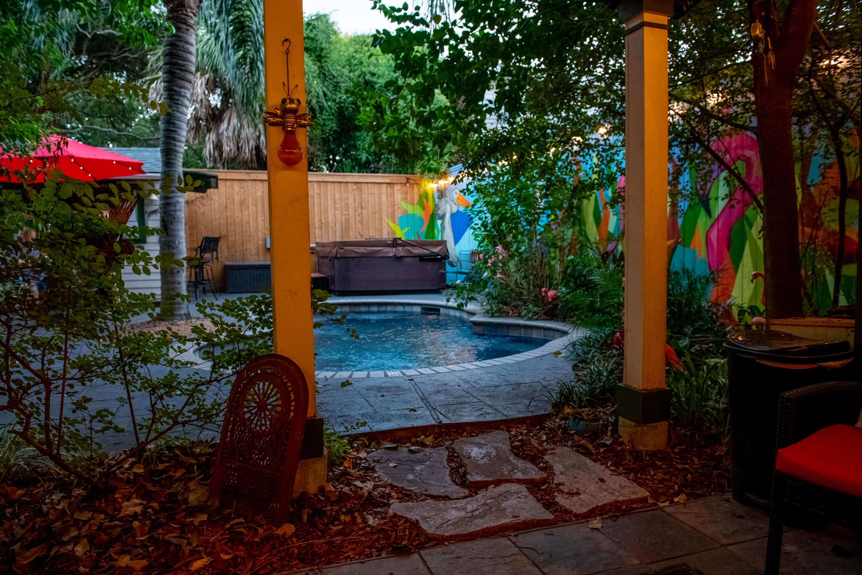 A covered outdoor area with a pool, wooden deck, and colorful murals.