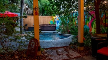 A covered outdoor area with a pool, wooden deck, and colorful murals.