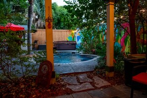 Un espacio al aire libre techado con piscina, terraza de madera y murales coloridos.
