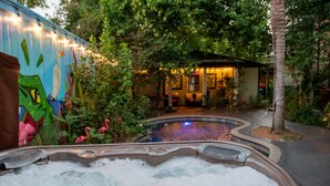 Un jacuzzi rodeado de abundante vegetación y un mural.
