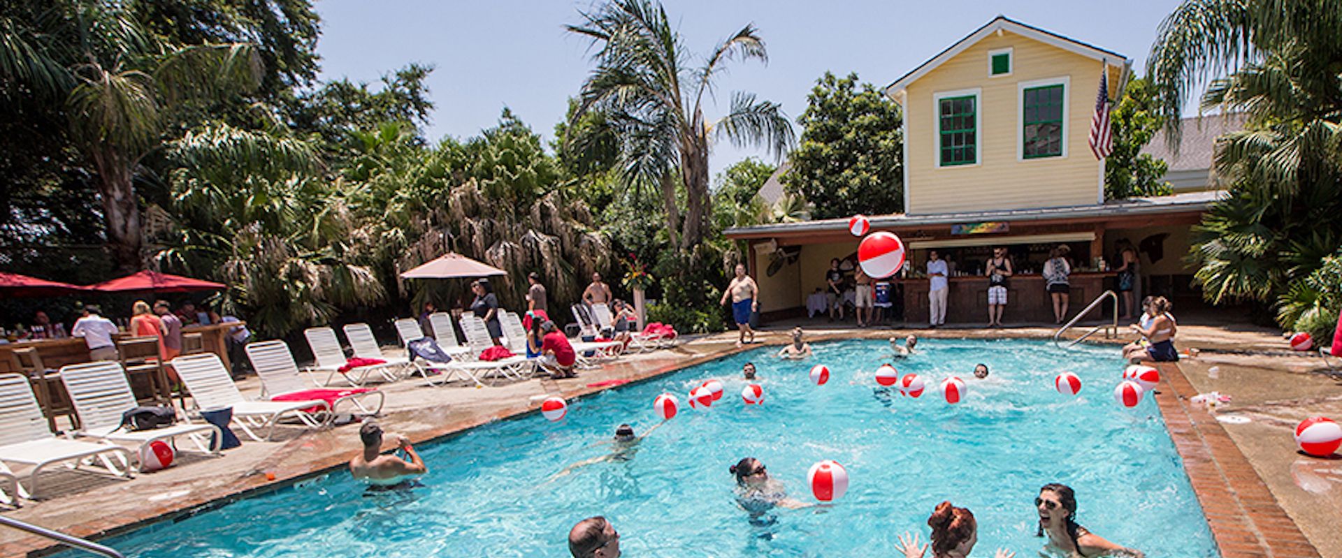 Zona de piscina con sillas de descanso y un edificio al fondo.