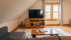 Una sala de estar acogedora con un televisor sobre un mueble de madera, un sofá y una mesita de centro.