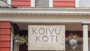 Un edificio con fachada roja y un letrero blanco que dice "Koivu Koti EST. 1870".