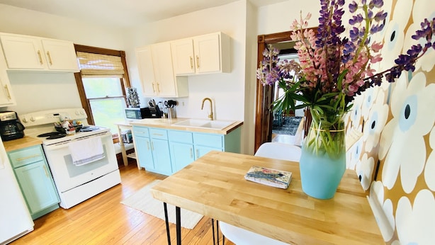 Una cocina moderna con armarios azul claro, una mesa de comedor de madera y un ventanal grande.