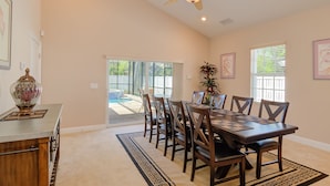 A spacious dining area with a large table and chairs, a ceiling fan, and a view of a backyard with a pool. - Olde Florida Style, 4 Bedrooms 3 Bath Pool\Hot Tub - Free Pool and Spa Heat! (Naples)