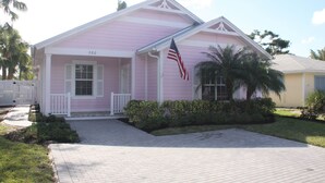 A pink house with a white porch, an American flag, and a mailbox. - Olde Florida Style, 4 Bedrooms 3 Bath Pool\Hot Tub - Free Pool and Spa Heat! (Naples)
