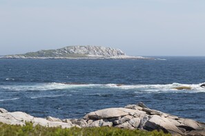 A coastal landscape with rocky outcrops and a distant island. - Idyllic Oceanfront Cottage, Near Peggy's Cove! (Prospect)