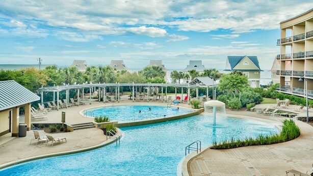 Een resort met een groot zwembad, diverse ligbedden en uitzicht op de oceaan.