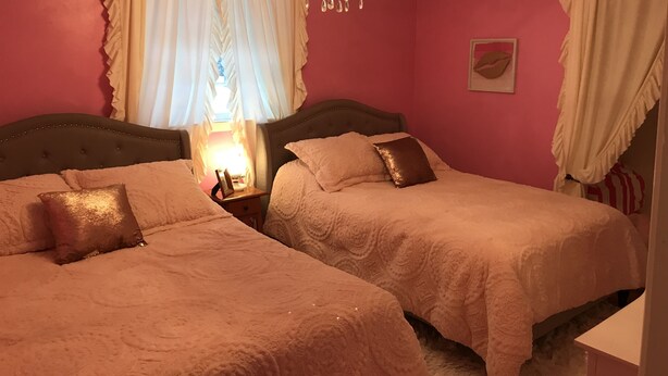Une chambre avec deux lits, un lustre et une fenêtre avec des rideaux.