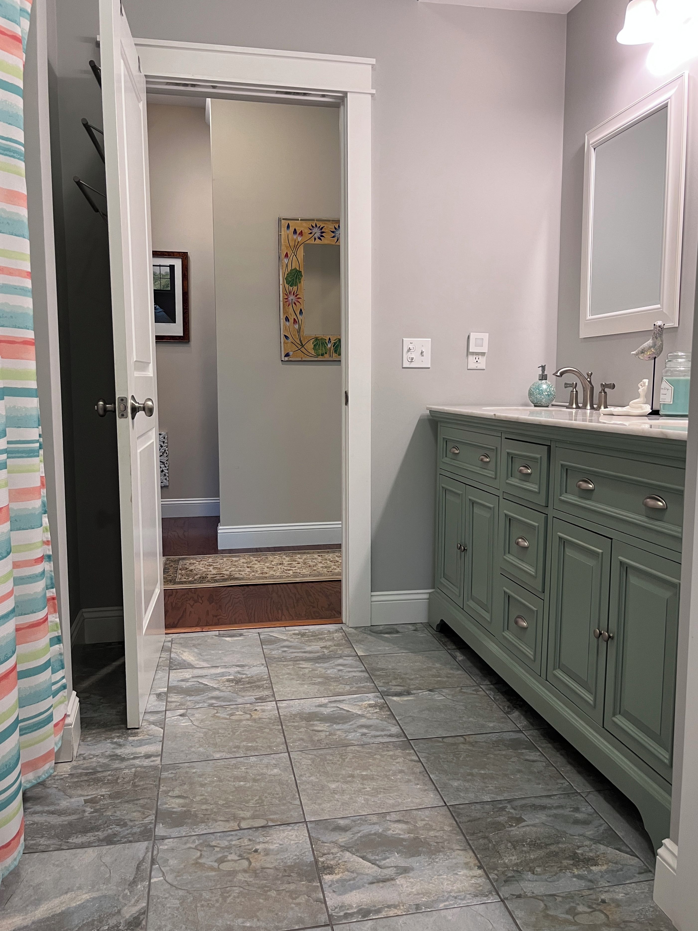 A bathroom with a green vanity, a mirror, and a shower area.