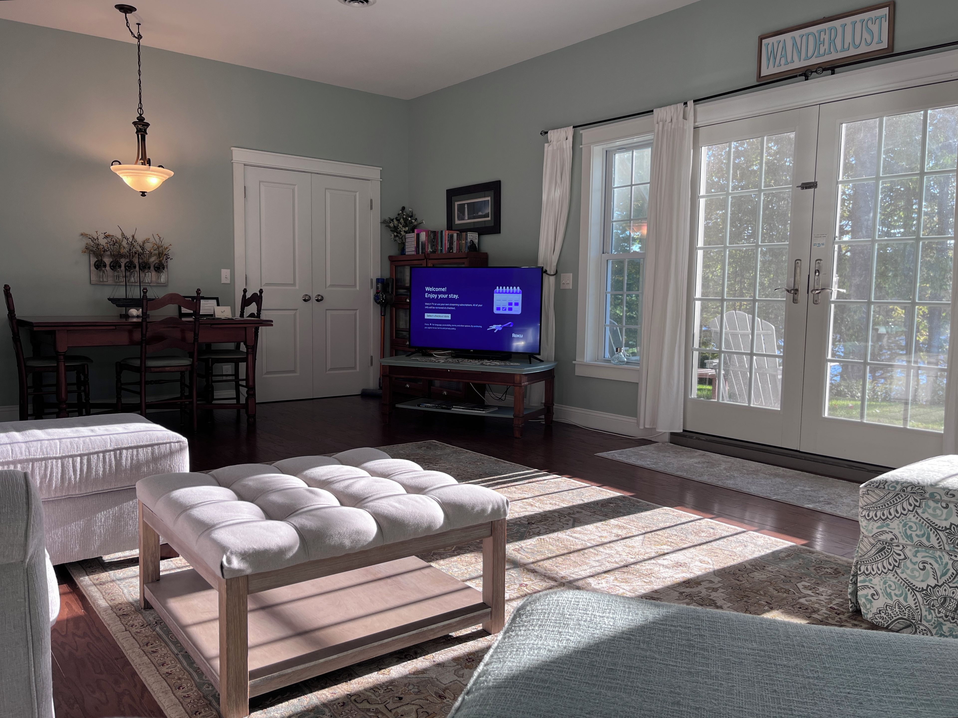 A living room with a television, a dining area, and a large window with curtains.