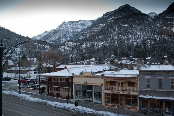 A town with buildings, a street, and snow-covered mountains in the background.