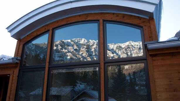 Un edificio con ampie finestre che riflettono un paesaggio montano.