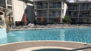 Una piscina con jacuzzi, sillas de descanso y sombrillas.