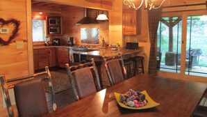 A wooden cabin interior with a dining area, kitchen, and a view of the outdoors. - Luxury Cabin Nestled In The Beautiful Blue Ridge Mountains (Boonsboro)