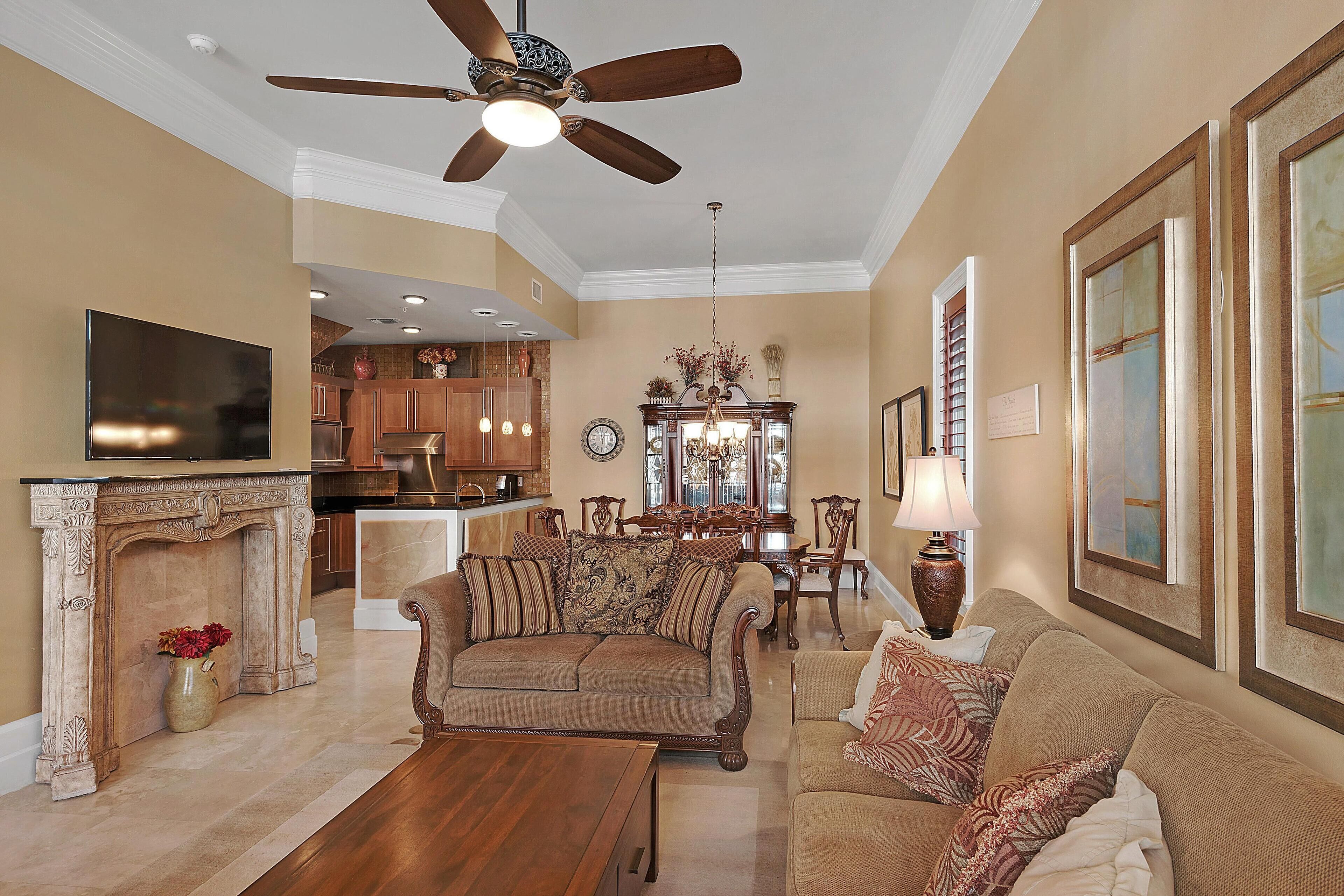 A spacious living room with a fireplace, a ceiling fan, and a dining area with a chandelier.