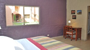 Un dormitorio con cama, ventana, escritorio y silla.