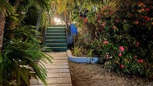 A pathway leading to a building entrance surrounded by lush greenery and flowering plants. - Miraflores Boutique Hotel (San Andrés)