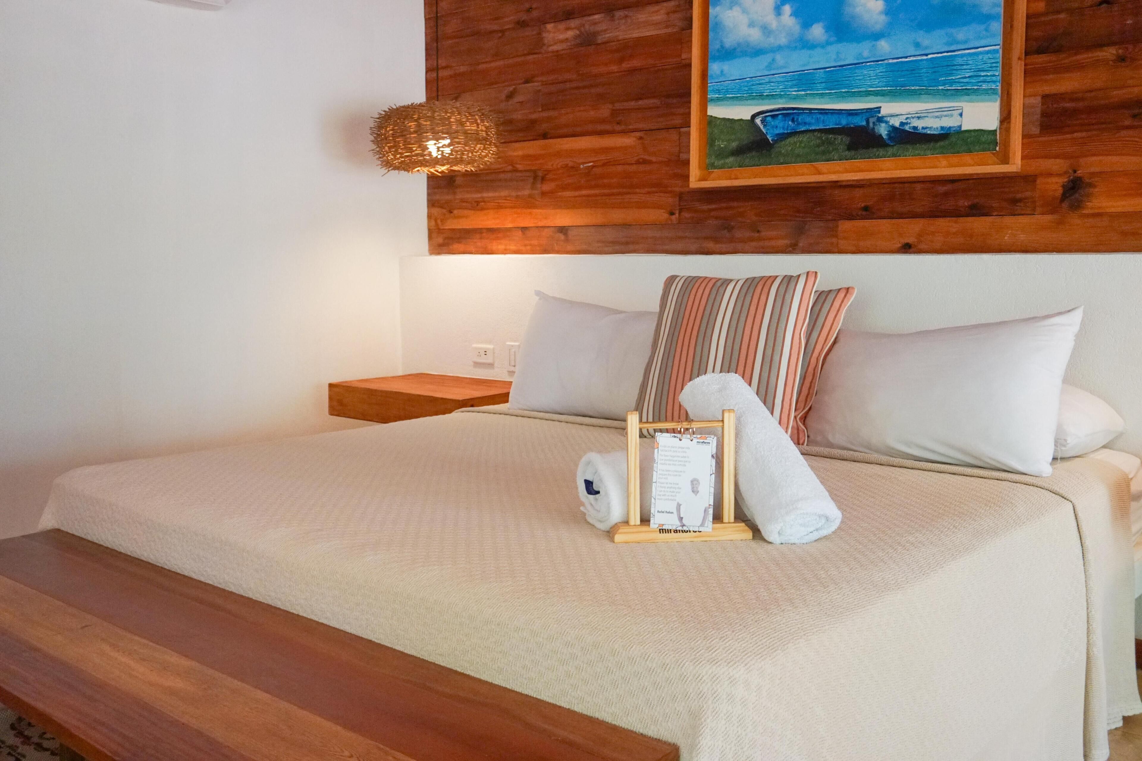 A neatly made bed with a wooden headboard, a nightstand, and a framed picture on the wall.