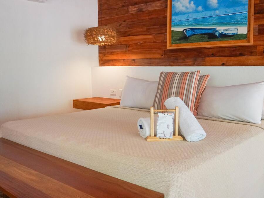 A neatly made bed with a wooden headboard, a nightstand, and a framed picture on the wall.