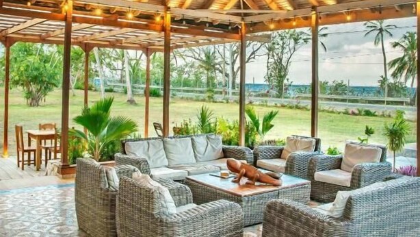 An outdoor covered patio with wicker furniture, a wooden ceiling, and a view of the ocean. - Miraflores Boutique Hotel (San Andrés)