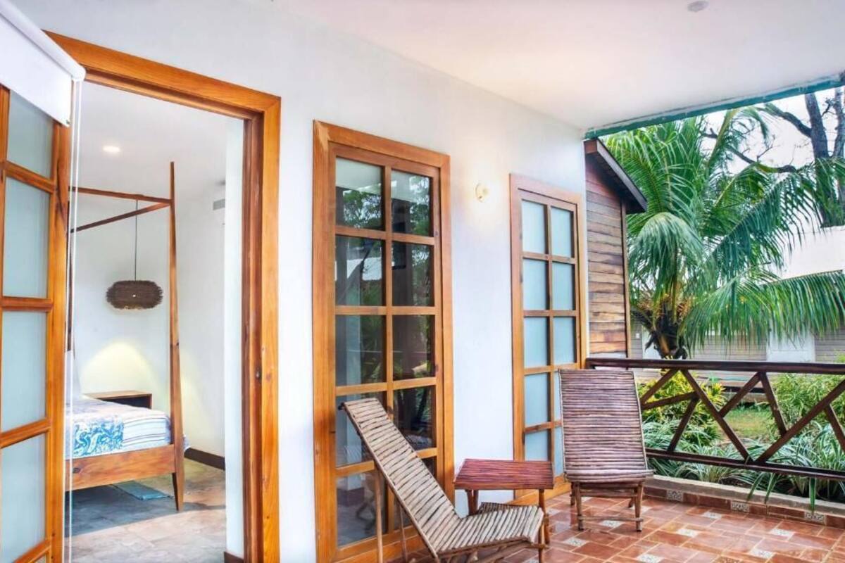 Una habitación con cama, una mesita, una silla y un balcón con vista a zonas verdes.