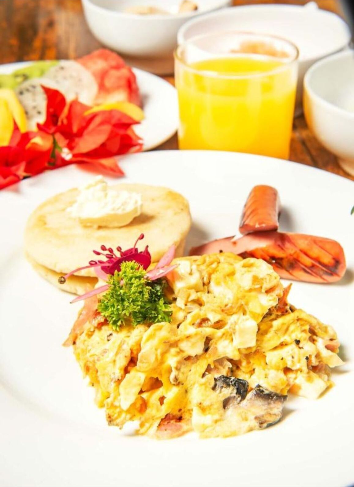 A breakfast plate with scrambled eggs, a pastry, and a side of fruit.