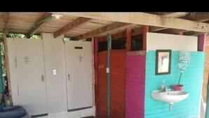 Une petite salle de toilettes fermée, avec deux portes, un lavabo et un baril bleu.