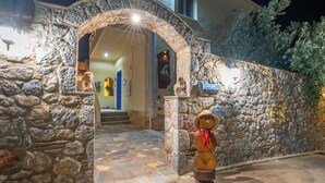 A stone archway leading to a building entrance at night. - Maistros Studios (Delphi)