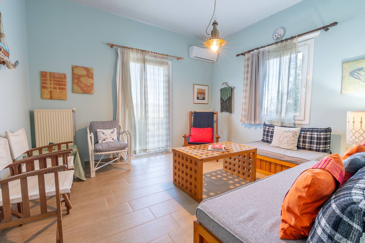 A cozy room with a bed, a wooden table, a chair, and a window with curtains.