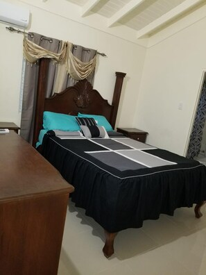 Un dormitorio con cama, cómoda de madera y mesita de noche.