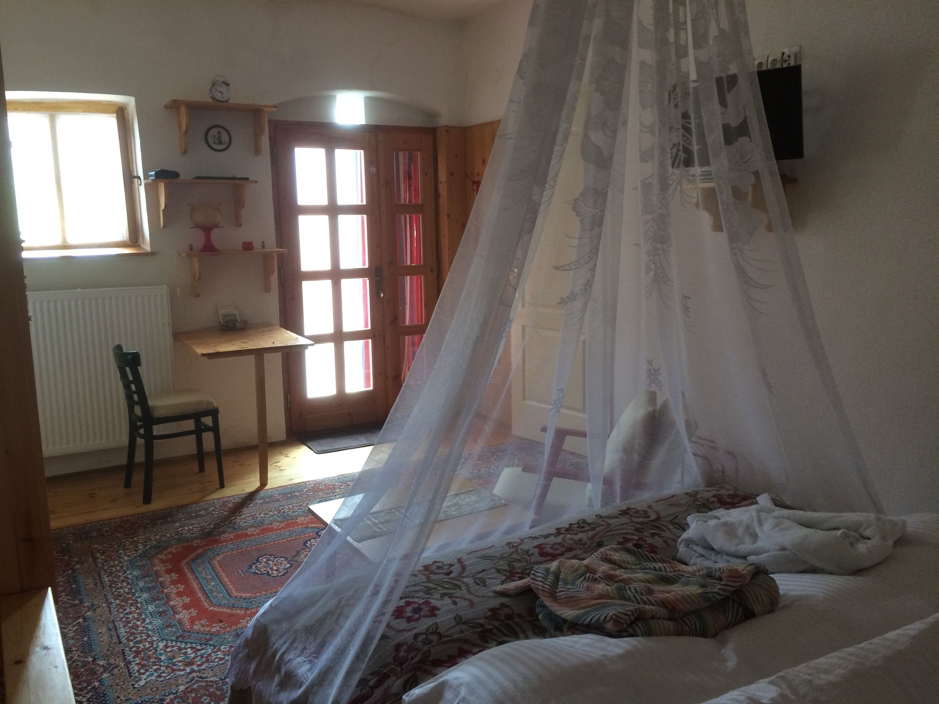 A bedroom with a bed, a chair, a desk, and a window.