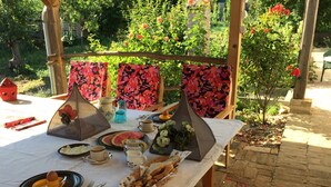 An outdoor dining setup with a table, chairs, and a garden view. - Farmotel Stefania (Szakadat)