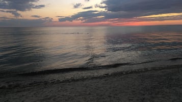 Una playa con aguas tranquilas y un atardecer.