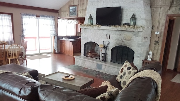 Ein Wohnzimmer mit Kamin, Ledersofa und Essbereich mit Tisch und Stühlen.
