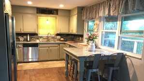 Una cocina moderna con una isla central, taburetes de bar y una ventana con vistas.