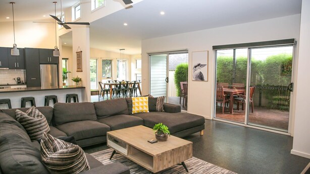 A modern living room with a sectional sofa, a wooden coffee table, and a sliding glass door leading to an outdoor patio. - DECKED OUT AT BRIGHT : Bright (Bright)
