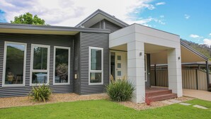 A modern two-story house with large windows, a covered porch, and a well-maintained lawn. - DECKED OUT AT BRIGHT : Bright (Bright)