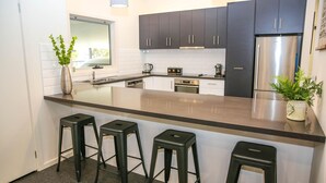 A modern kitchen with dark cabinets, stainless steel appliances, and a central island with bar stools. - DECKED OUT AT BRIGHT : Bright (Bright)
